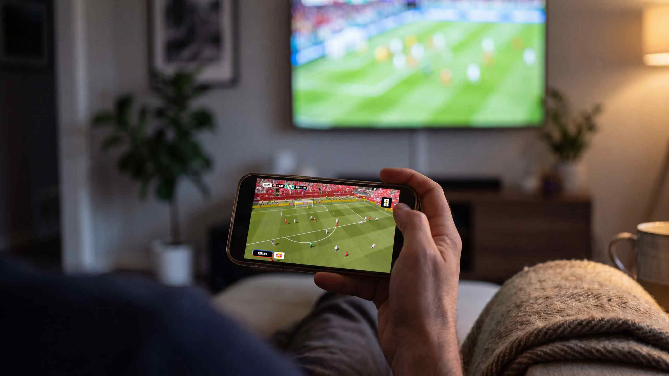 A man watching soccer on two different screens.